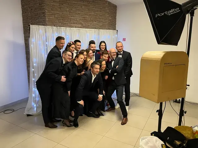 Skupina hostí pri fotobúdke s bielym pozadím a svetlami