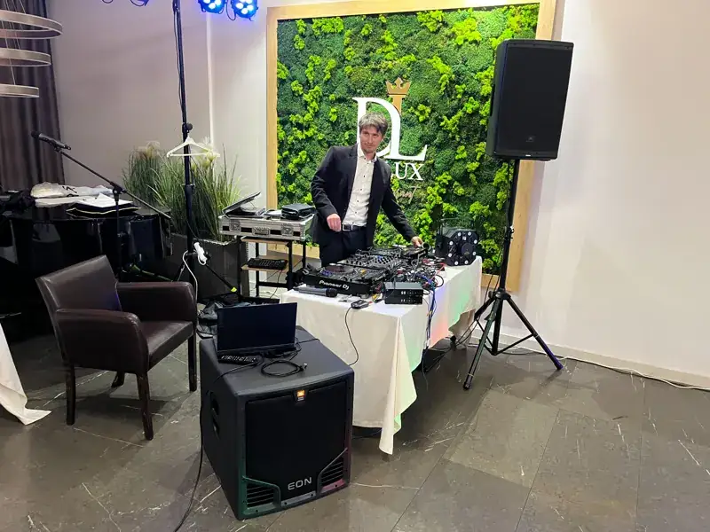 DJ za mixpultom s ozvučením a svetlami na večernej akcii
