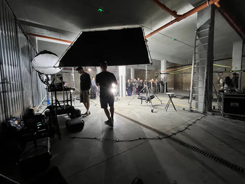 Natáčanie videoklipu v hale s veľkým zatieňovacím rámom a štábom